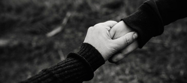 Two hands clasped together, symbolizing support and connection.