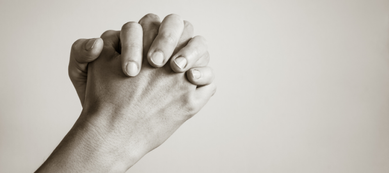Close-up of clasped hands, showing detail of skin and fingernails.