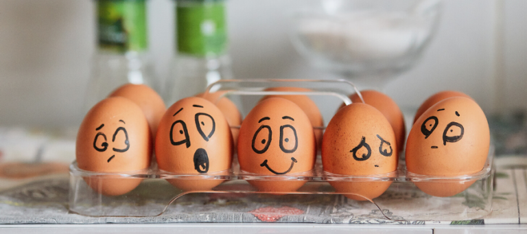 Eggs with drawn-on faces expressing various emotions. Illustrates evolutionary psychology concepts.