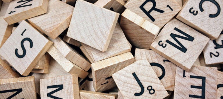 Scrabble tiles scattered, letters visible. Evolutionary psychology concept.