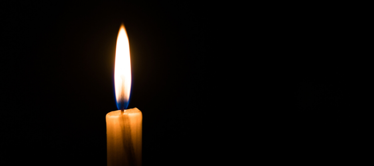 Single lit candle in the dark.