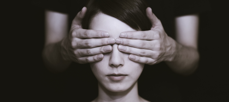 Close-up of a woman's face, hands covering her eyes, symbolizing disagreement or conflict.
