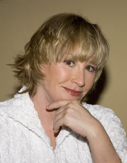Headshot of a blonde woman, smiling slightly, hand resting on her chin.