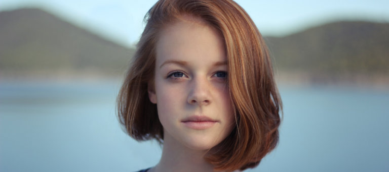 Thoughtful young woman looking at camera, contemplating environmental issues.