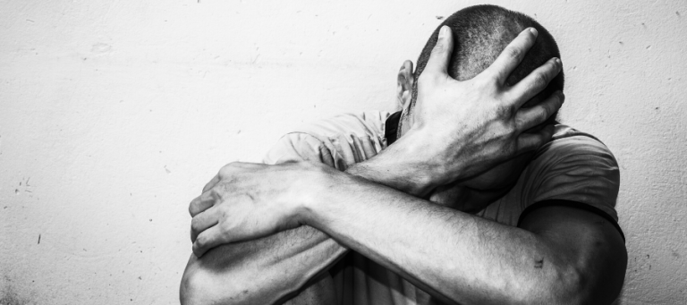 Man sits alone, head in hands, conveying feelings of despair and the absurd.