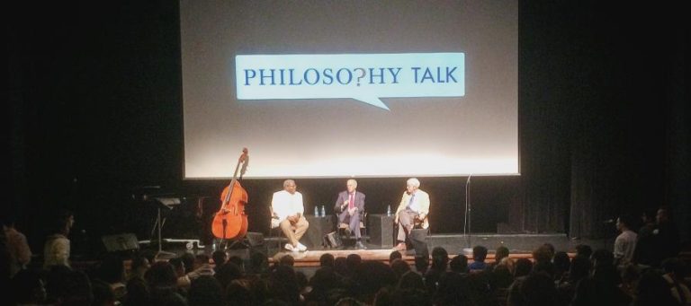 Three men on stage at a Philosophy Talk, a double bass sits to the side.