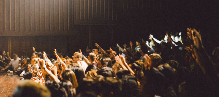 Large crowd of people with raised hands at a conference or event.
