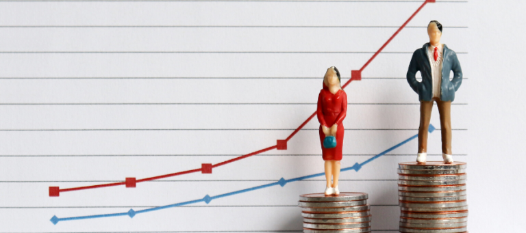 Miniature figures stand atop stacks of coins illustrating a pay gap.