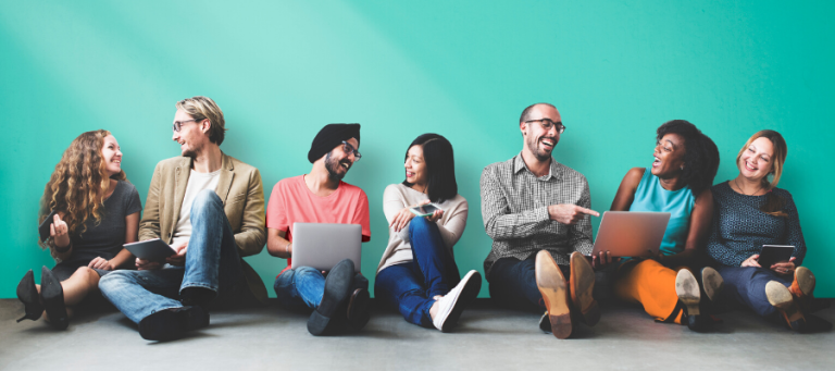 Diverse group of young adults sitting together, using laptops and tablets.