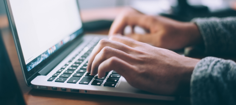 Close-up of hands typing on a laptop keyboard.