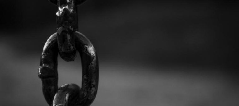 Close-up of a dark, weathered chain link.