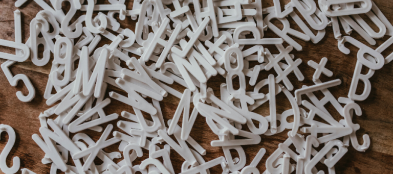 White plastic letters and numbers scattered on a wooden surface.