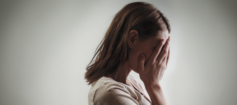 Woman covering her face with her hands, appearing distressed.