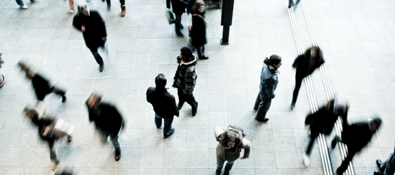 Blurred people walking in a city, conveying a sense of anonymity and urban movement.