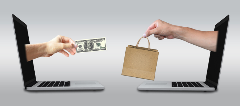 Hands reaching from laptops exchange a $100 bill for a paper shopping bag. Online shopping transaction.
