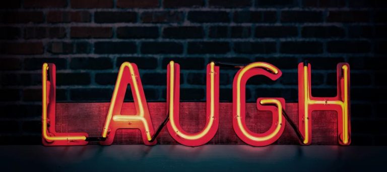 Neon sign reading "LAUGH," perfect for a blog about rough humor.