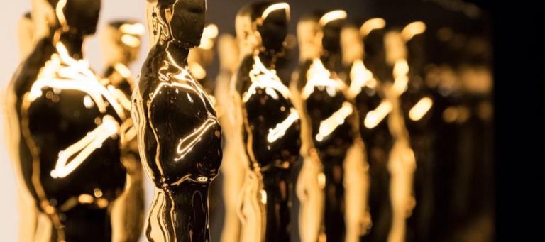 Close-up of several golden Oscar statuettes.