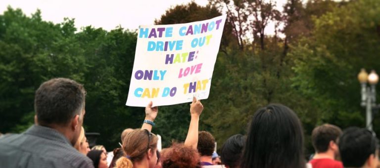 Protestors hold sign: "Hate cannot drive out hate; only love can do that.