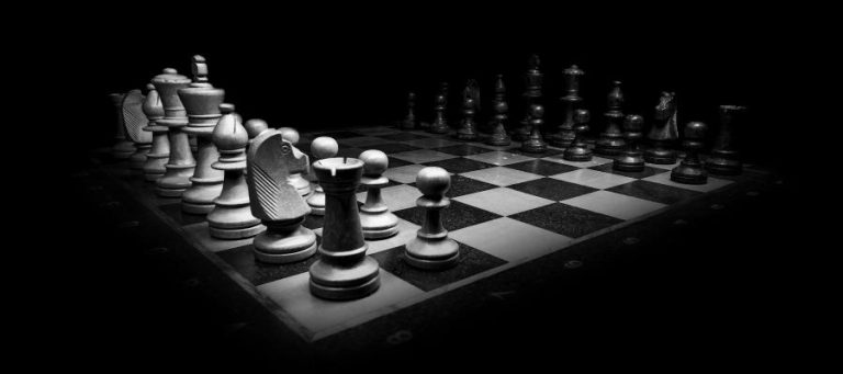 Chessboard with black and white pieces set up for a game.