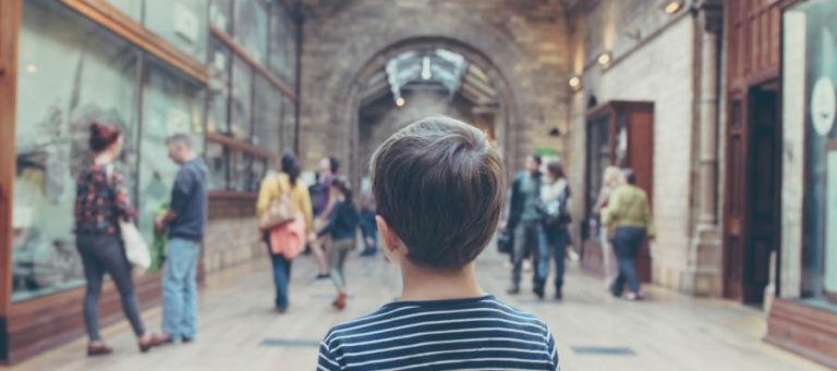 Child looking at museum exhibits, pondering access to the arts.