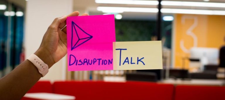 Hand holding sticky notes: "Disruption" and "Talk".