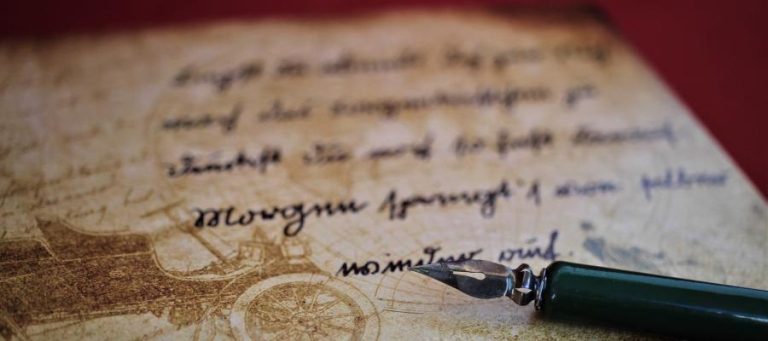 Antique quill pen rests on aged paper with handwritten text.
