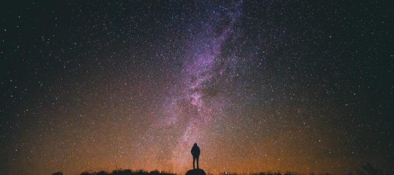 Silhouette of a person standing before a starry night sky, Milky Way visible.