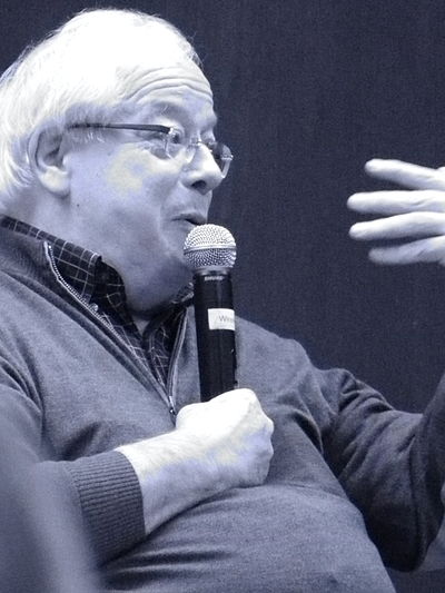 Professor discussing philosophy and film at a conference, holding a microphone.