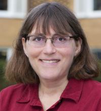 Headshot of a woman with glasses, wearing a red shirt.