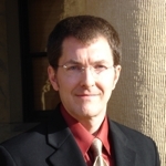 Headshot of a man wearing glasses and a suit.