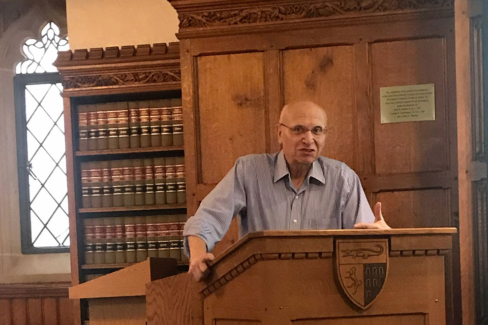 Man giving a lecture on war crimes at a lectern.