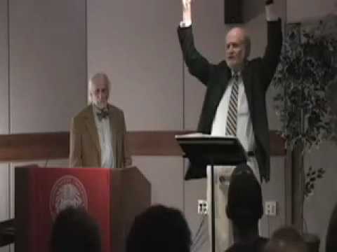 Two men giving a presentation, one animatedly gesturing, illustrating philosophy through humor.