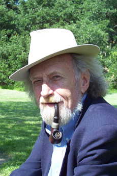 Older man with long gray hair, wearing a hat and smoking a pipe.