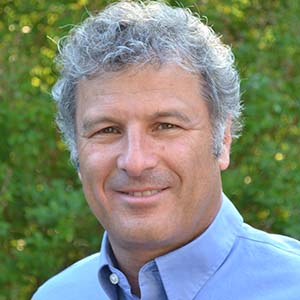 Headshot of a middle-aged man with graying hair, wearing a light blue collared shirt.