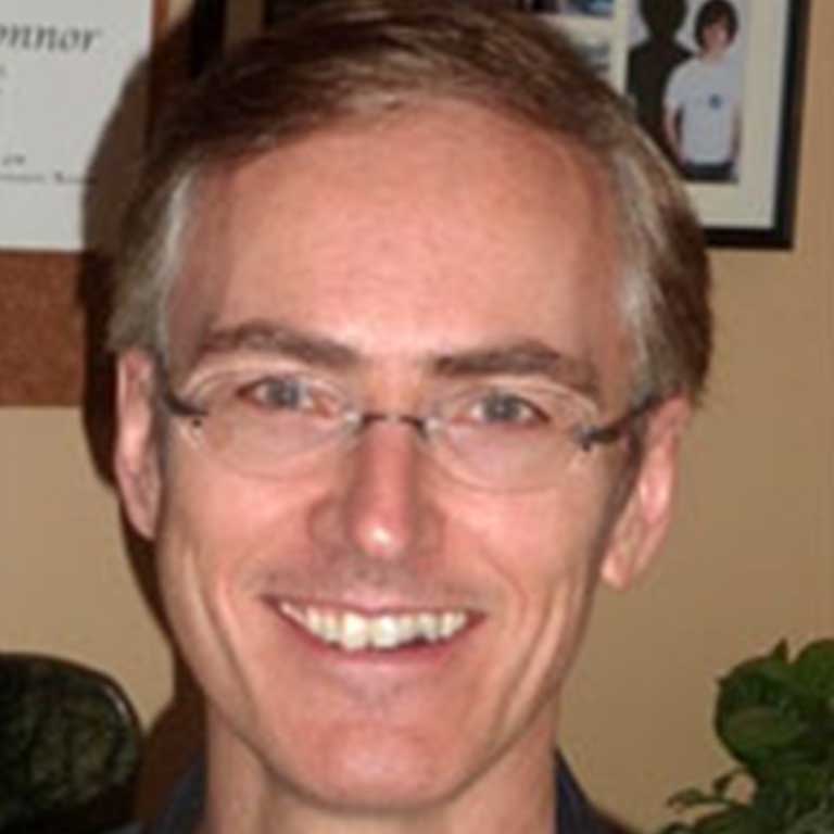 Headshot of a man wearing glasses, possibly discussing levels of reality.