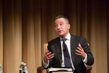 Man in suit speaking at a conference, discussing privacy rights.