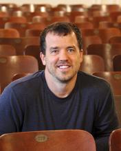 Man sitting in an auditorium, reflecting on the evolution of storytelling.