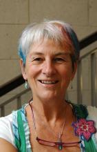 Portrait of a smiling woman with short, partially blue and pink hair.