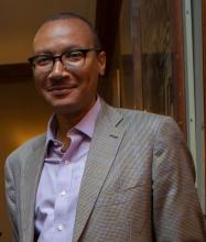 Headshot of a man wearing glasses and a suit jacket