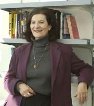 Portrait of a woman leaning against bookshelves.