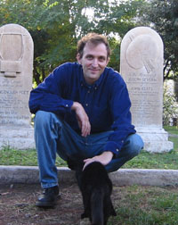 Man squatting next to a black cat near headstones; exploring narrative and self.