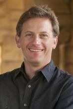 Headshot of a smiling man, possibly discussing education and culture wars.