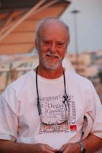 Smiling older man wearing a white t-shirt with text.