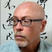 Portrait of a balding man with glasses, thoughtful expression.